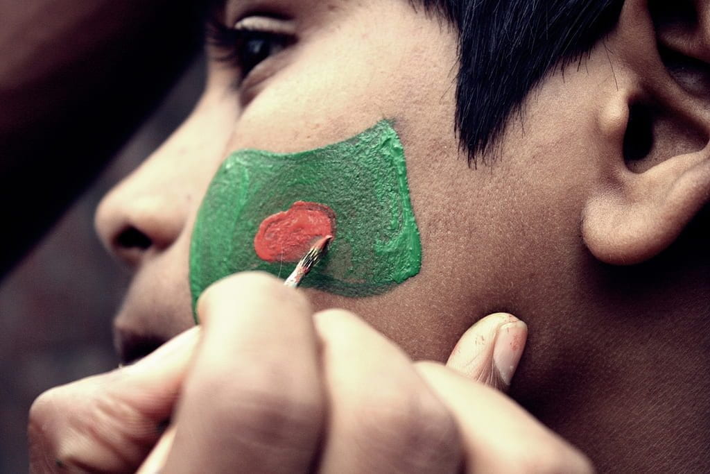 A boy has the flag of Bangladesh painted on his face.