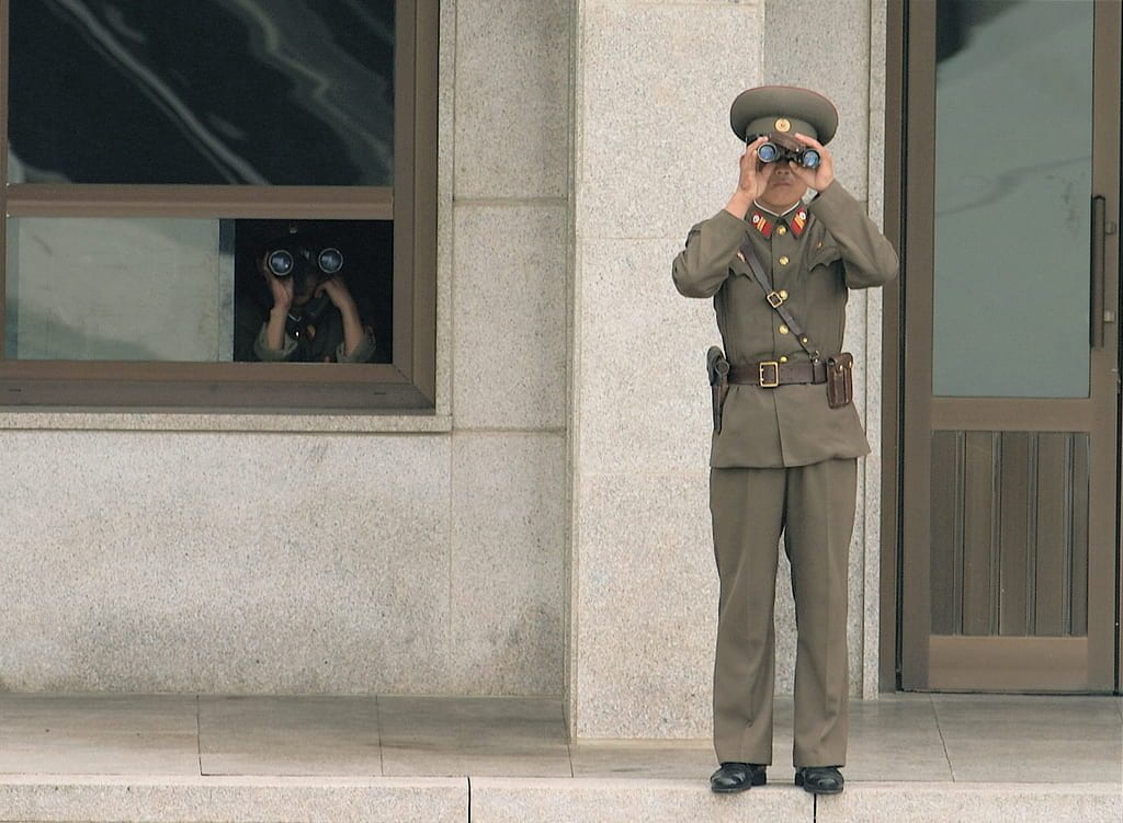a picture of two North Korean soldiers looking through binoculars towards the South