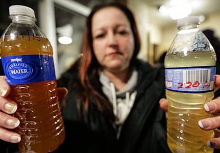 A woman holds water bottles filled with contaminated water in Flint