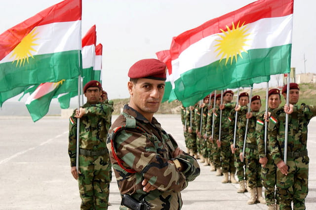 Kurdish soldiers salute the Kurdish flag.