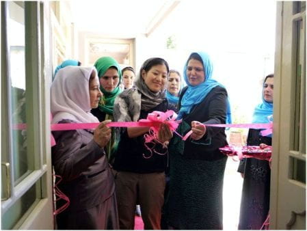 A group of hijabi women cut a ribbon to open the new shelter.
