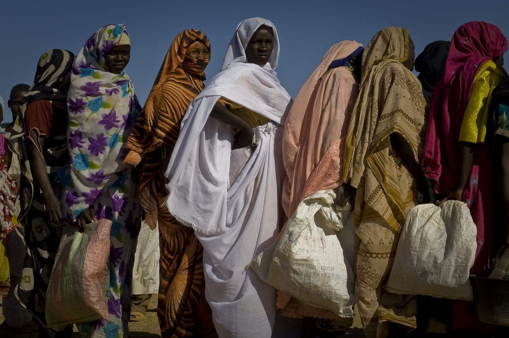 A group of refugee women stand in a line.