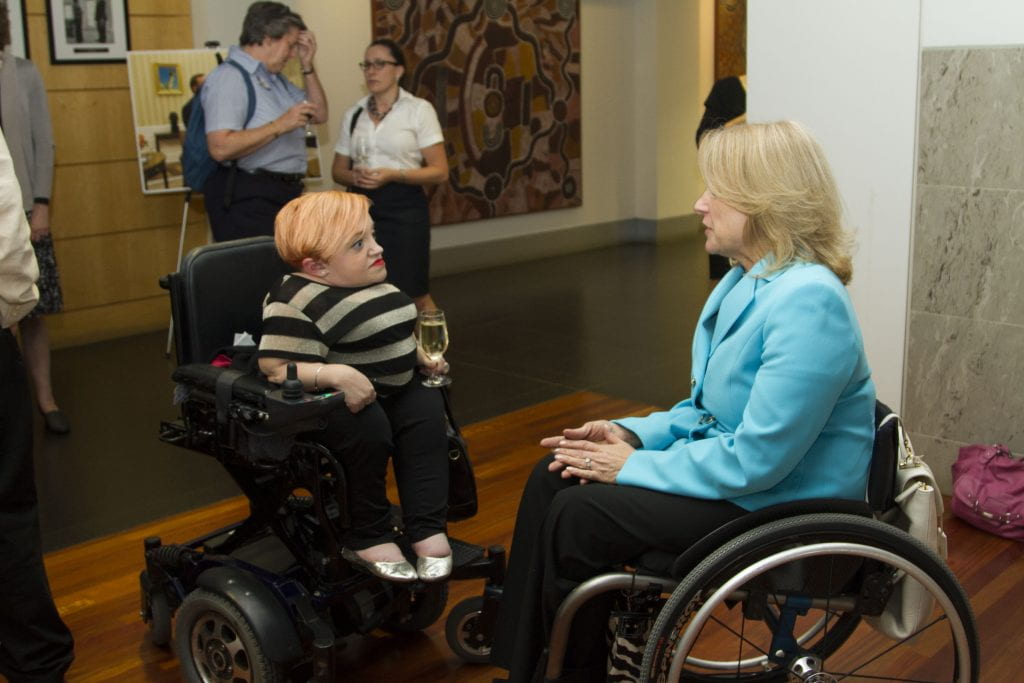 Disability activist Stella Young chats with Paralympic medalist Ann Cody. Both women use wheelchairs. 