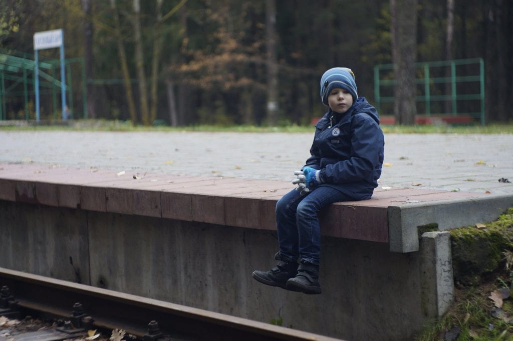 a lone little boy sitting on a platform