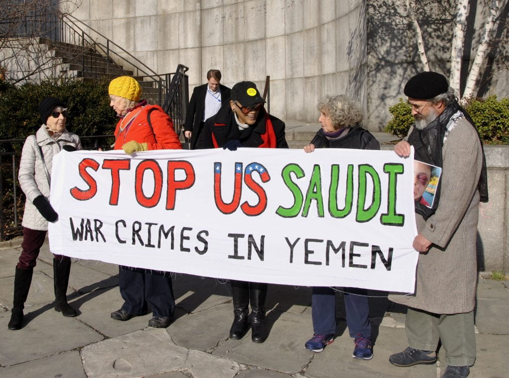 Group holding sign Reading "STOP US SAUDI WAR CRIMES IN YEMEN"
