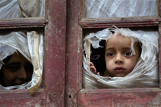 A child peeking out of torn plastic from a window
