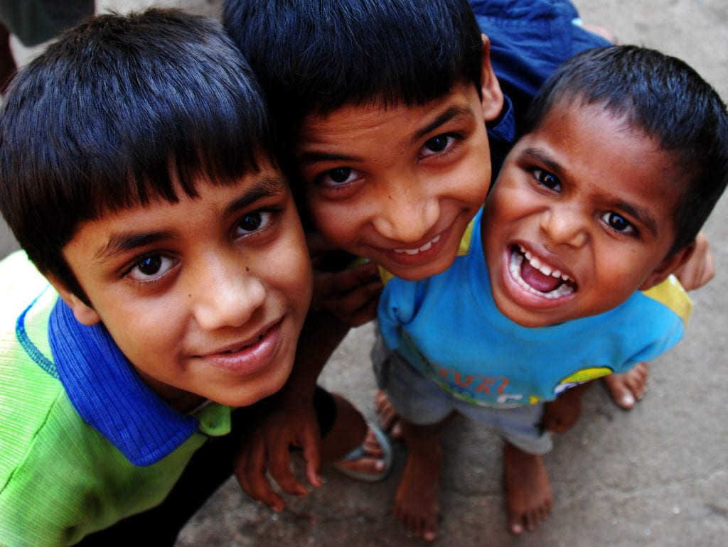 Three boys stare up at the camera, smiling. 