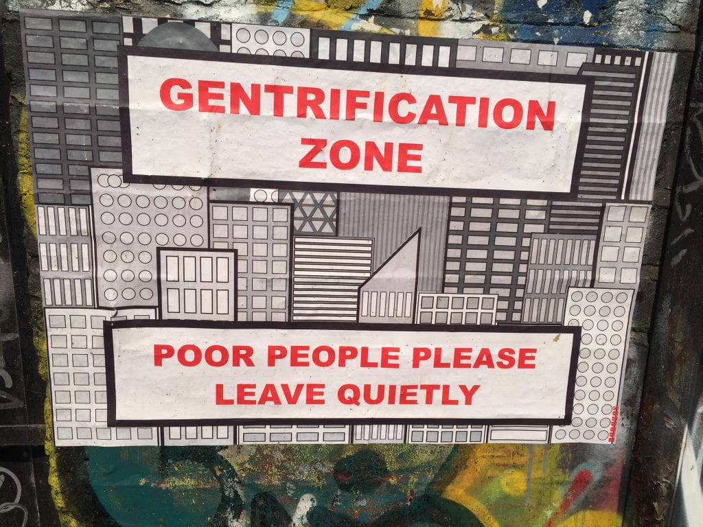 a sign that reads "Gentrification Zone, Poor people please leave quietly"