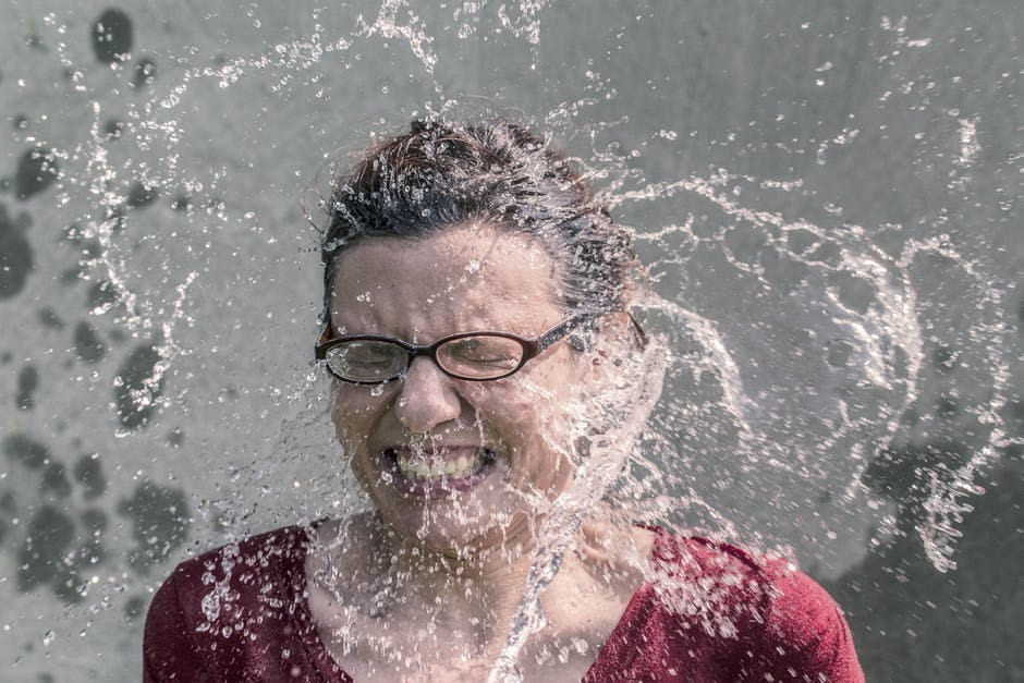 An image of a woman reacting to a splash of water from the top of her head. Basically a standard reaction from when someone does the Ice Bucket Challenge.