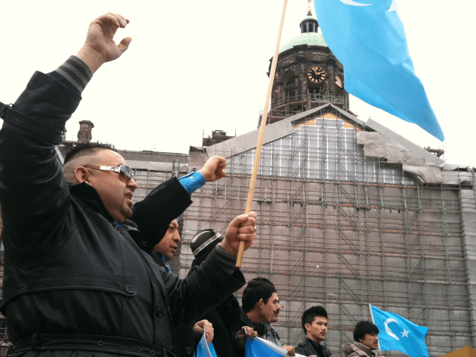 an Uyghur group holds their native flag while protesting repression against the Uyghur people