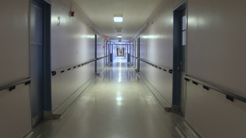 Narrowing hospital hallway with light at the end.