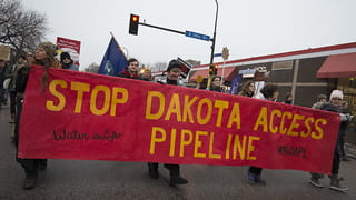 An image of protesters holding up a banner with the words "STOP DAKOTA ACCESS PIPELINE" across it.