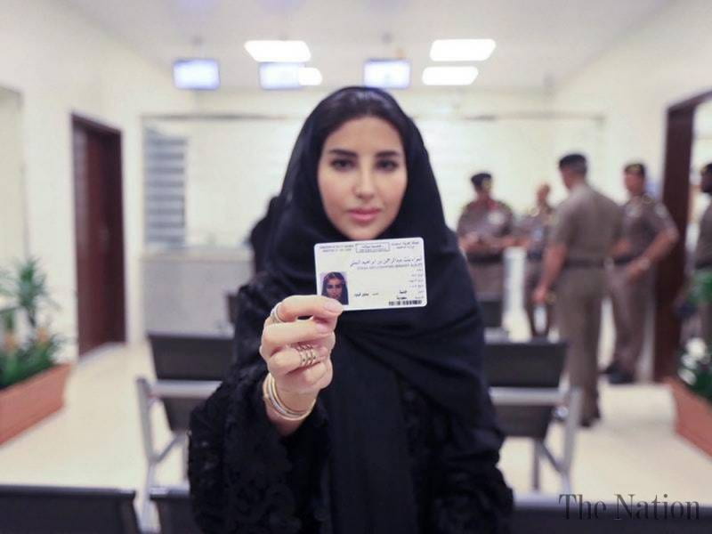 An image showing a Saudi Arabian woman holding up her driving license.