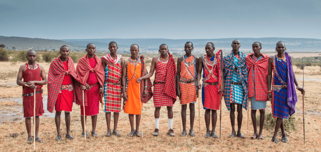 Photo showing Maasai men standing next to each other in a field.