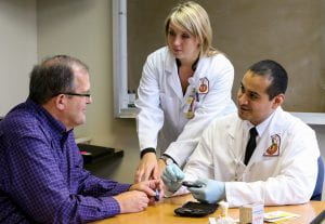 two doctors demonstrate glucometer to patient.