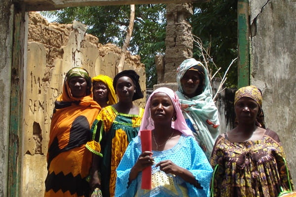 African women dressed in colorful robes standing in an unfinished building. They are doing an inspection.