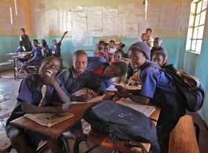 African school children in uniforms huddled around desks