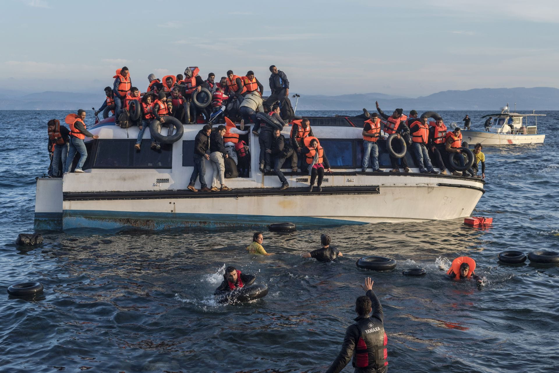 Image of a boat with dozens of refugees boarding