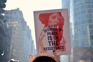 Yahoo Images, A woman is holding a poster which states “A woman’s place is in the resistance”