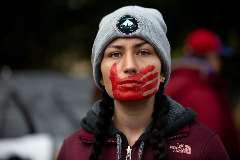 Indigenous women with red hand painted over the mouth, presenting the voiceless and missing indigenous women