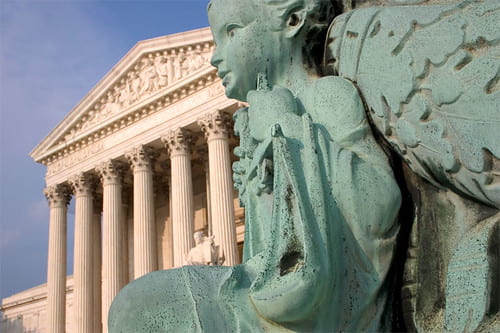 The image shows the sculpture of a women holding scales, which is supposed to represent justice. In the background are the pillars of the Supreme Court of the United States. 