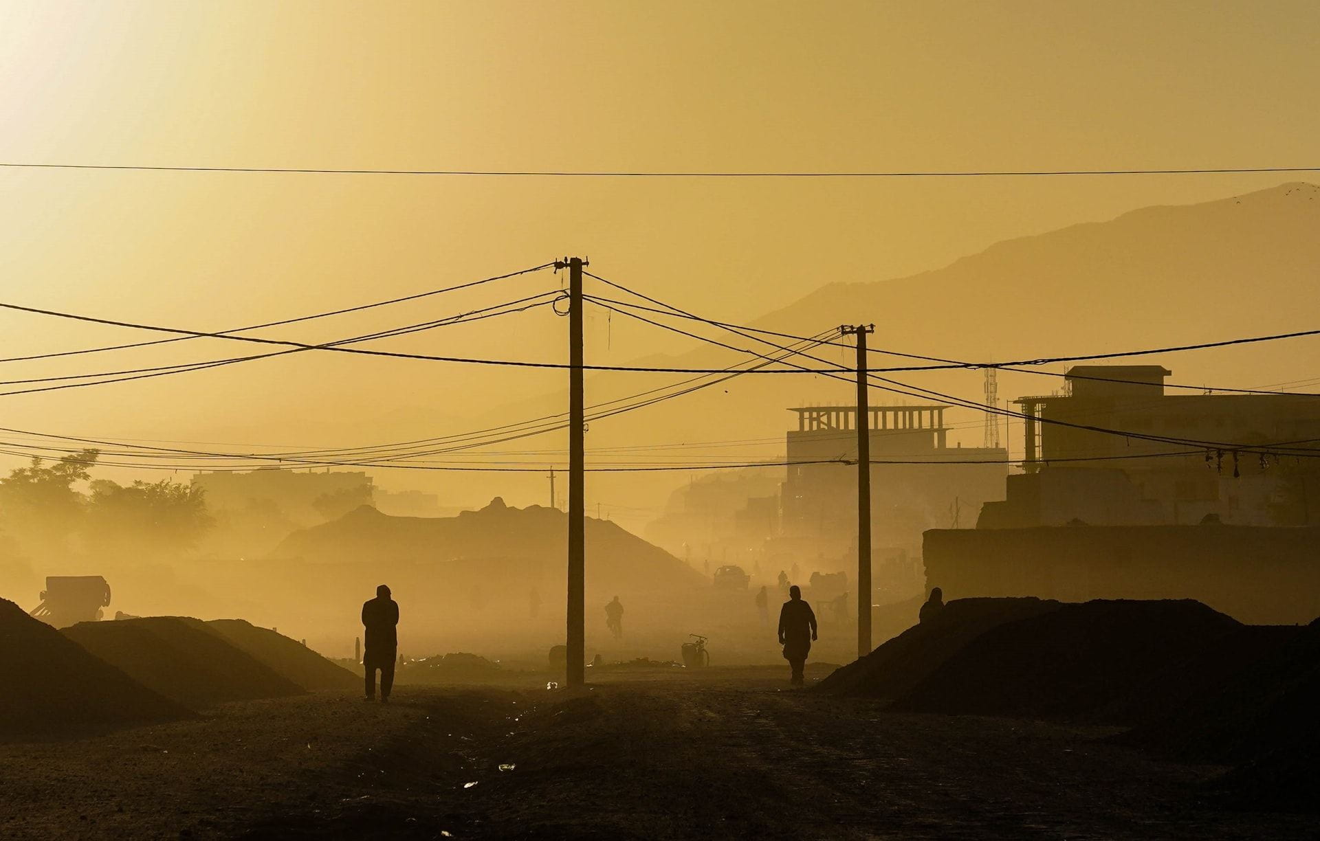 Dimly lit scene of a morning in Kabul, Afghanistan. Two silhouettes appear against the background.