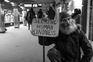 Photo of man holding sign that reads "Seeking Human Kindness"