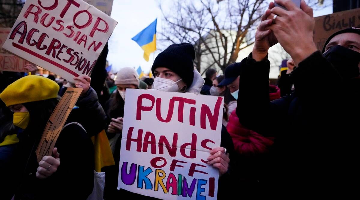 Photo of protestors holding sign that says "Putin hands off Ukraine"