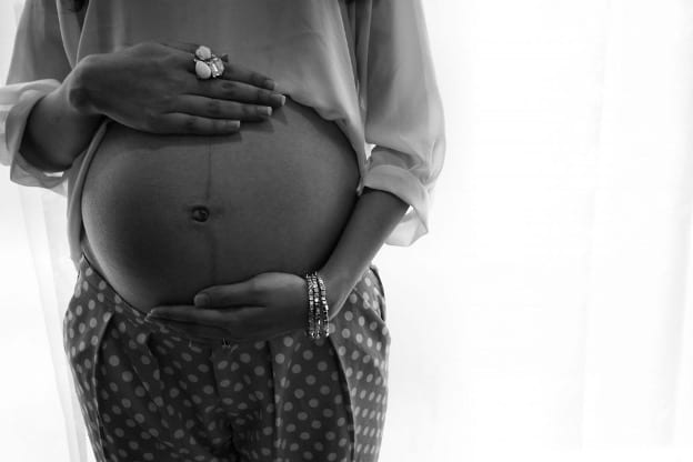 Woman holding her pregnant belly in B/W.