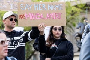 Protestors hold a sign that says "Say Her Name #MASHAAMINI"