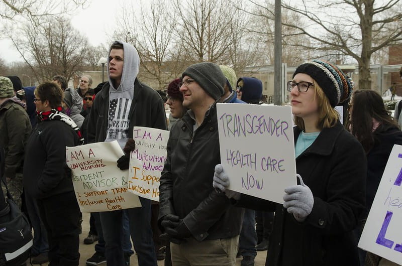 Image of protest with posters listing "Transgender Healthcare" 