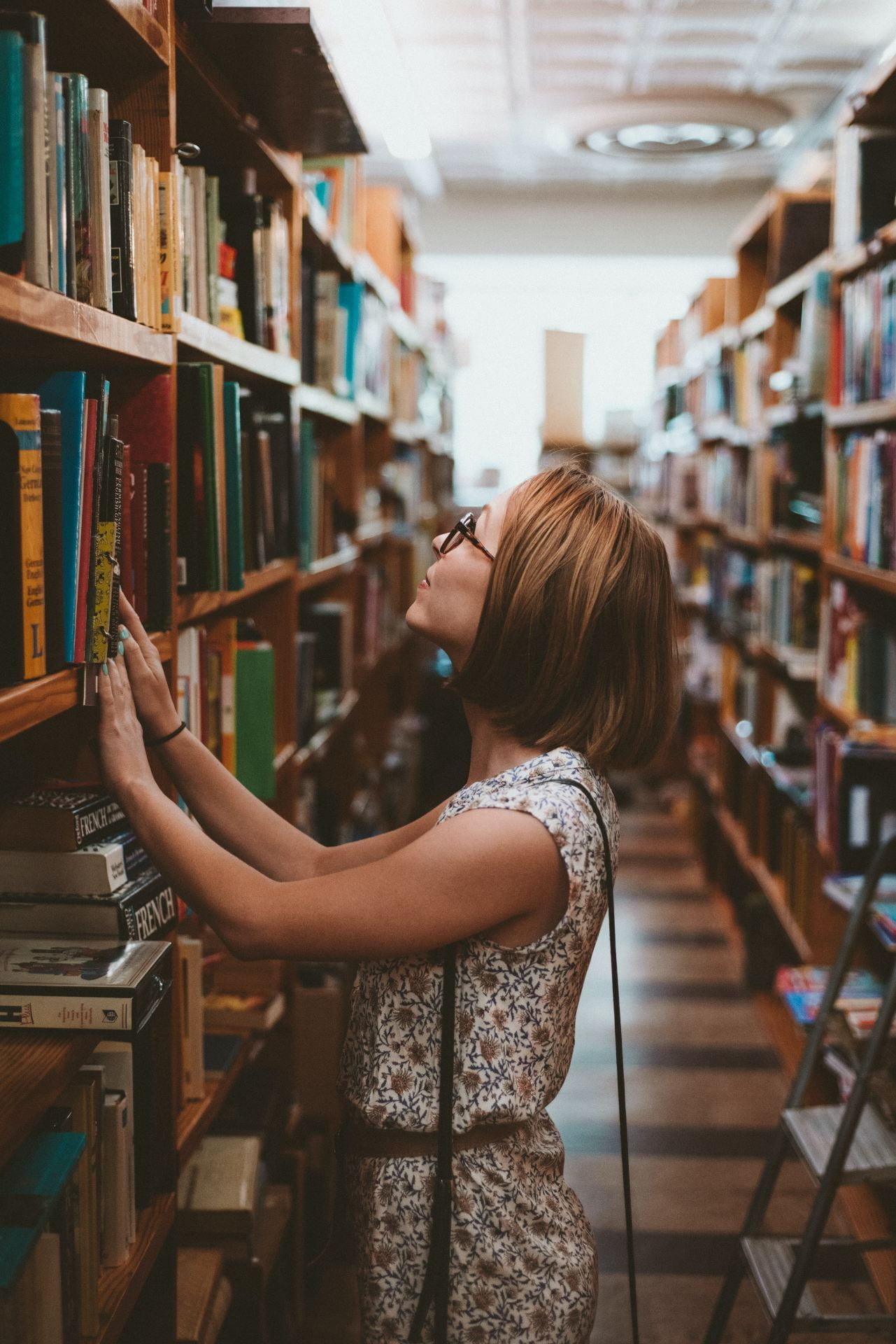 Woman looking through book spines in a bookstore.