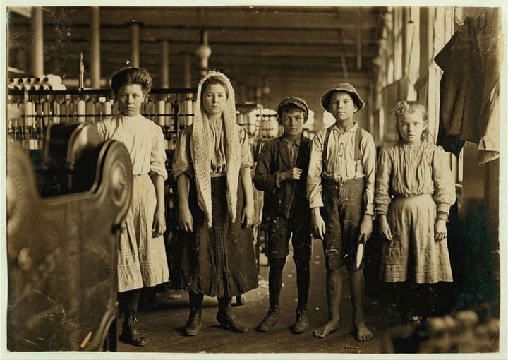 An image depicting young children posing in front of the heavy machinery they worked with inside the textile mills. 