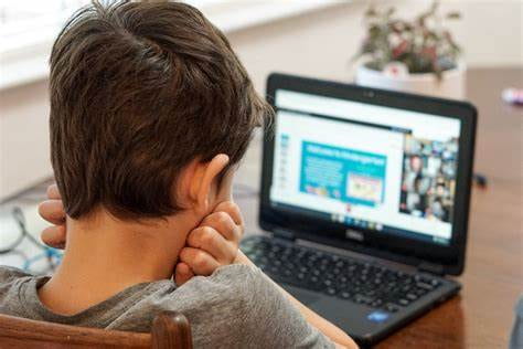 An image of a child sitting in front of a computer trying to learn virtually during COVID-19.