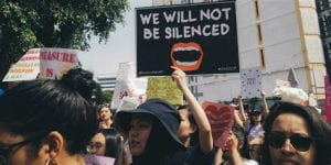 Picture of a poster at a protest stating "we will not be silenced" 