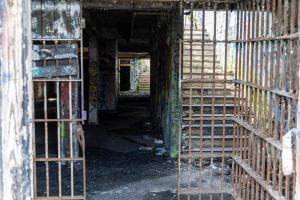 A set of bars within a decaying building structure covered in graffiti, formerly the now abandoned Atlanta Prison Farm. 