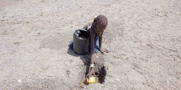 An image of a child in Kenya trying to find some clean water to drink. 