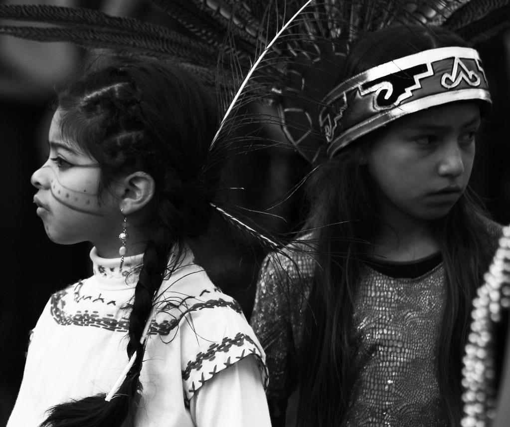 An image of two Native American children in their cultural garbs.