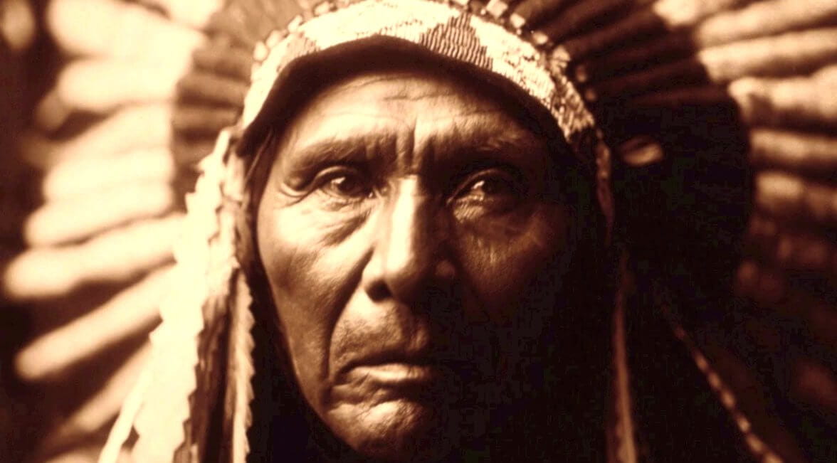 A Native American elder wearing a traditional headdress made of beads and feathers.
