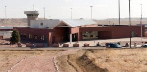 A slightly elevated shot of Florence Supermax prison, a red brick building surrounded by short grass and hills.
