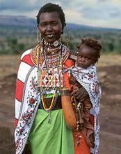 An image of a Maasai woman from Kenya holding her baby at her hips.