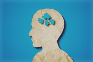Cutout of a head with puzzle pieces in brain